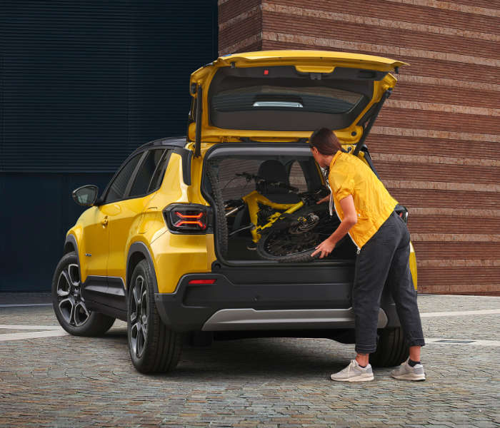 Jeep Avenger, дівчина кладе речі у відчинений багажник